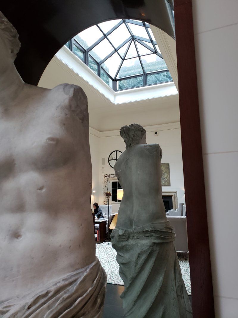 A statue of a man and a statue of a woman are reflected in a mirror