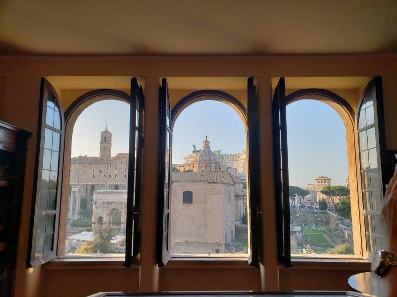 A room with three arched windows and a view of a city.