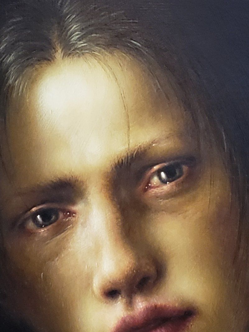 A close up of a woman 's face with a tear coming out of her eye.