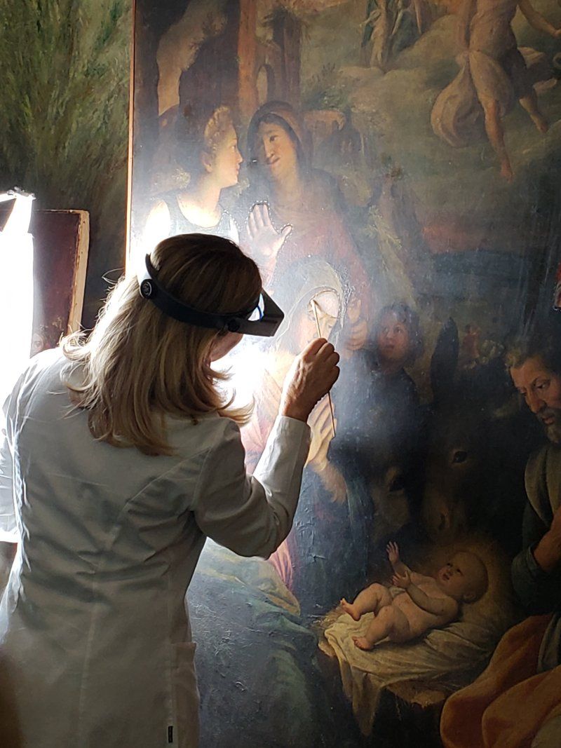 A woman is looking at a painting with a magnifying glass.