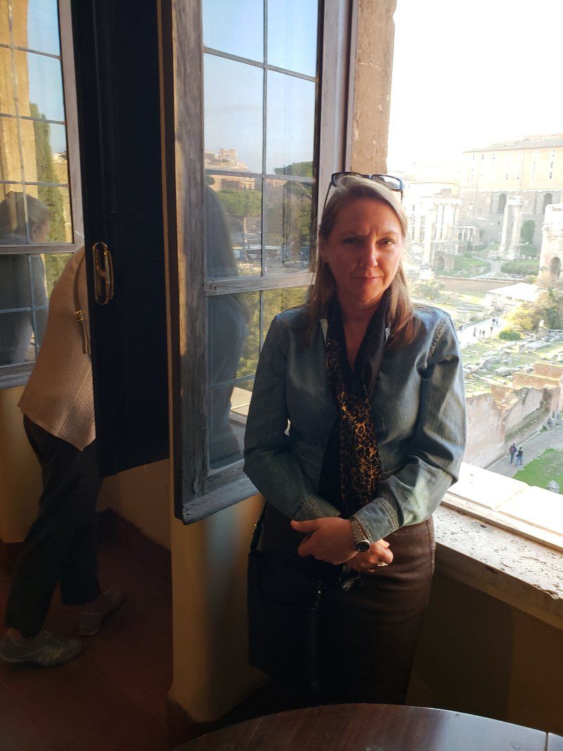 A woman is standing in front of a window with a view of a city.