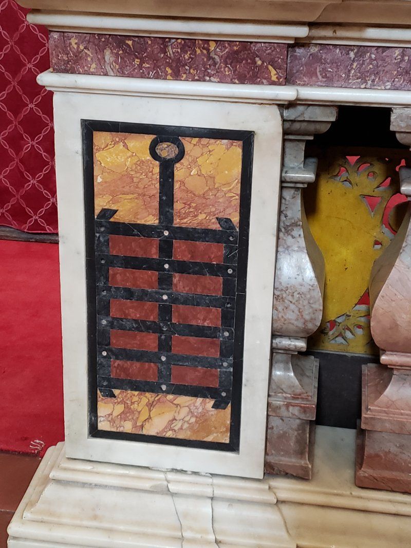 A door with a key on it is on a marble pillar in a church.