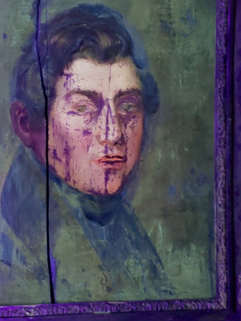 A close up of a painting of a man 's face in a purple frame.