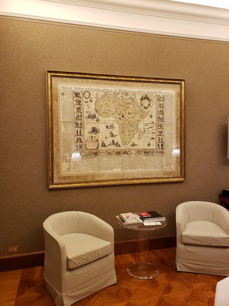 A living room with two chairs and a table and a large picture on the wall.