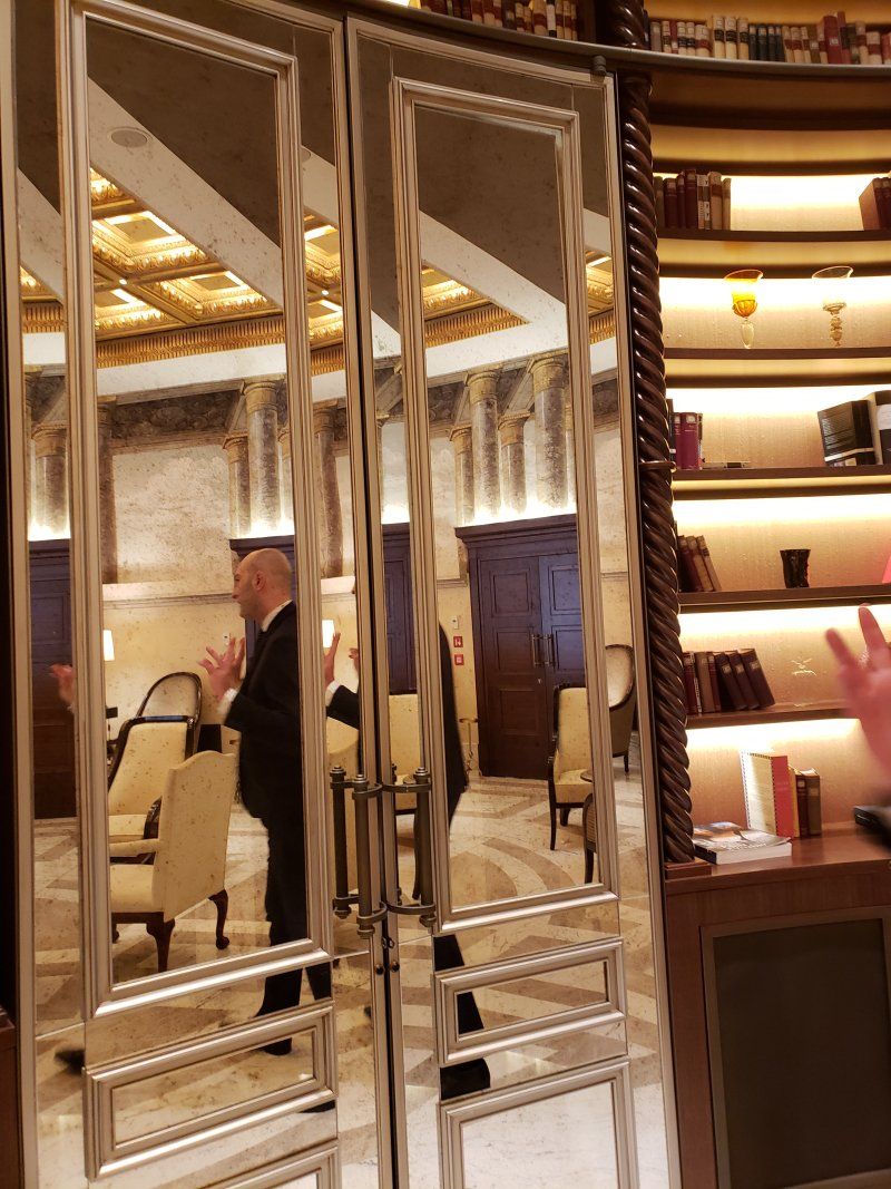 A man in a suit is standing in a room with mirrored doors
