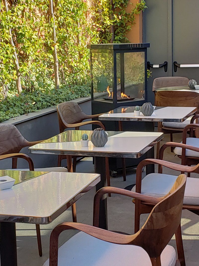 A patio with tables and chairs and a fireplace.