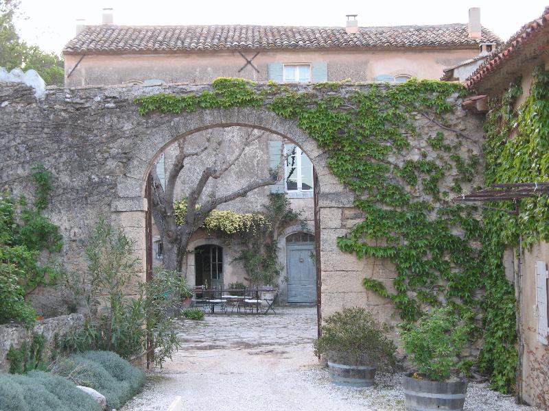 A stone archway leading to a building with a tree in front of it