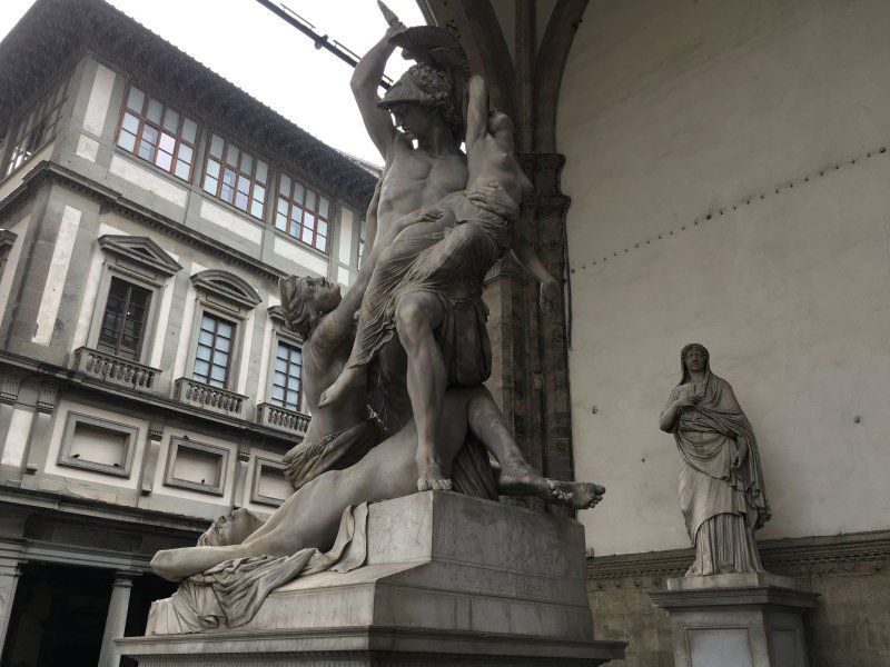 A statue of a man carrying a woman in front of a building