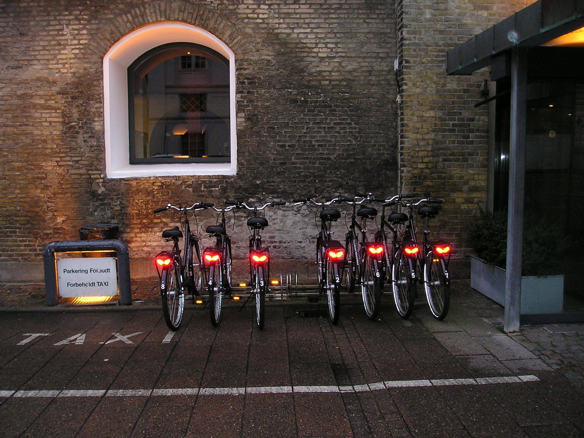 A row of bicycles are parked in front of a brick building