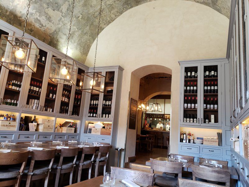 A restaurant with tables and chairs and lots of bottles on the shelves