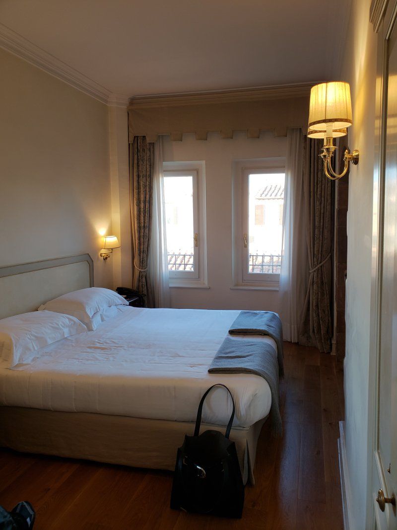 A hotel room with a large bed and two windows