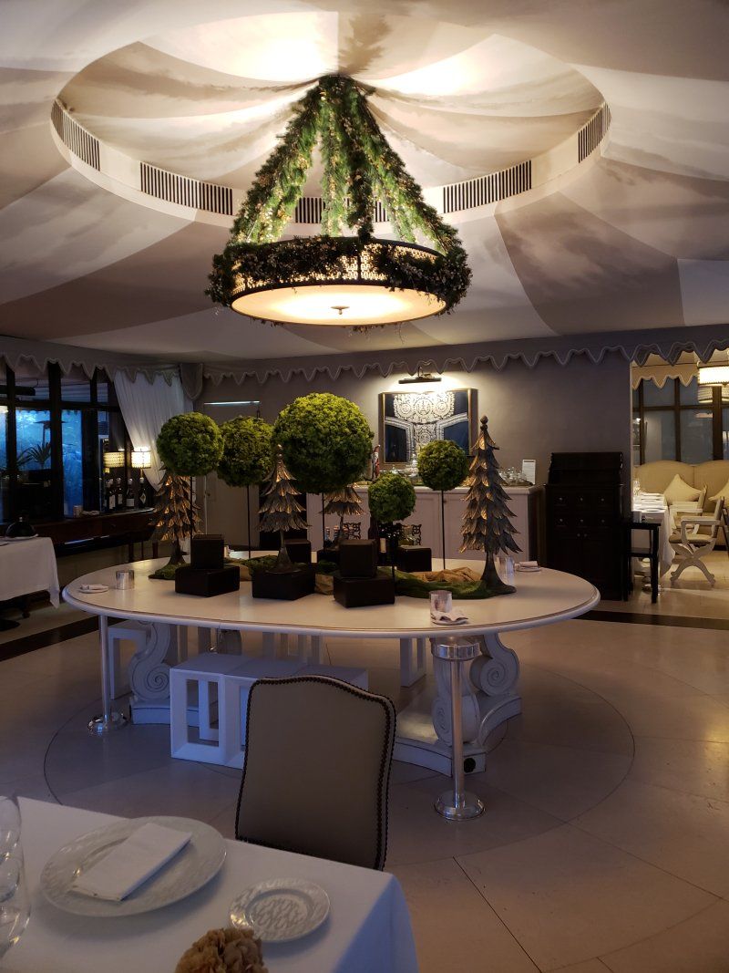 A room with a table and chairs and a chandelier hanging from the ceiling