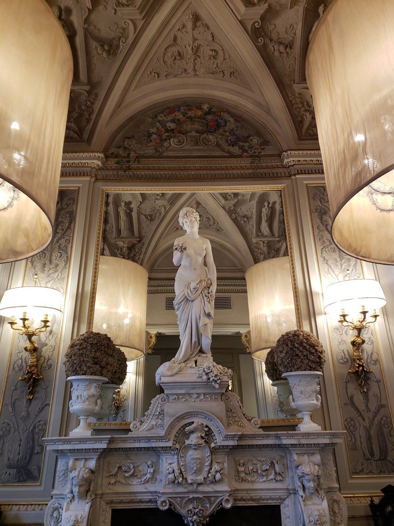 A statue of a woman is sitting on top of a fireplace in a room.