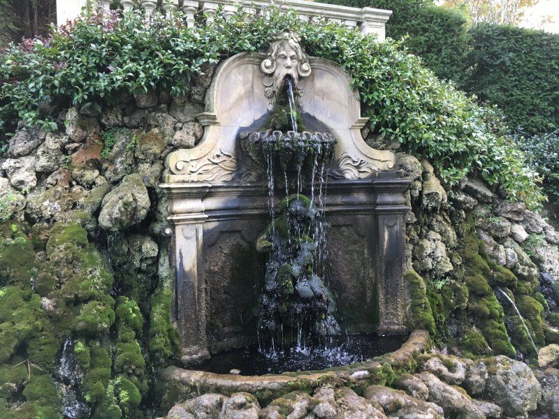 A waterfall is surrounded by rocks and moss in a park.