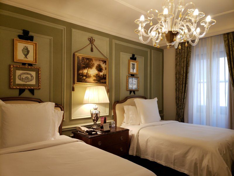 A hotel room with two beds and a chandelier.
