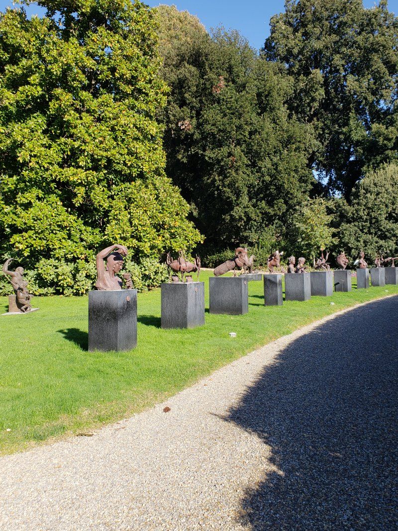 A row of statues sitting on top of concrete blocks in a park.
