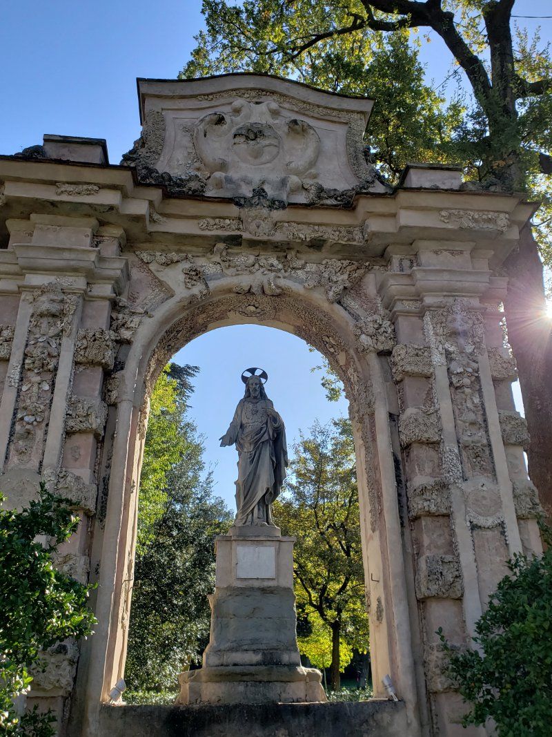 A statue of a man standing under an archway in a park.