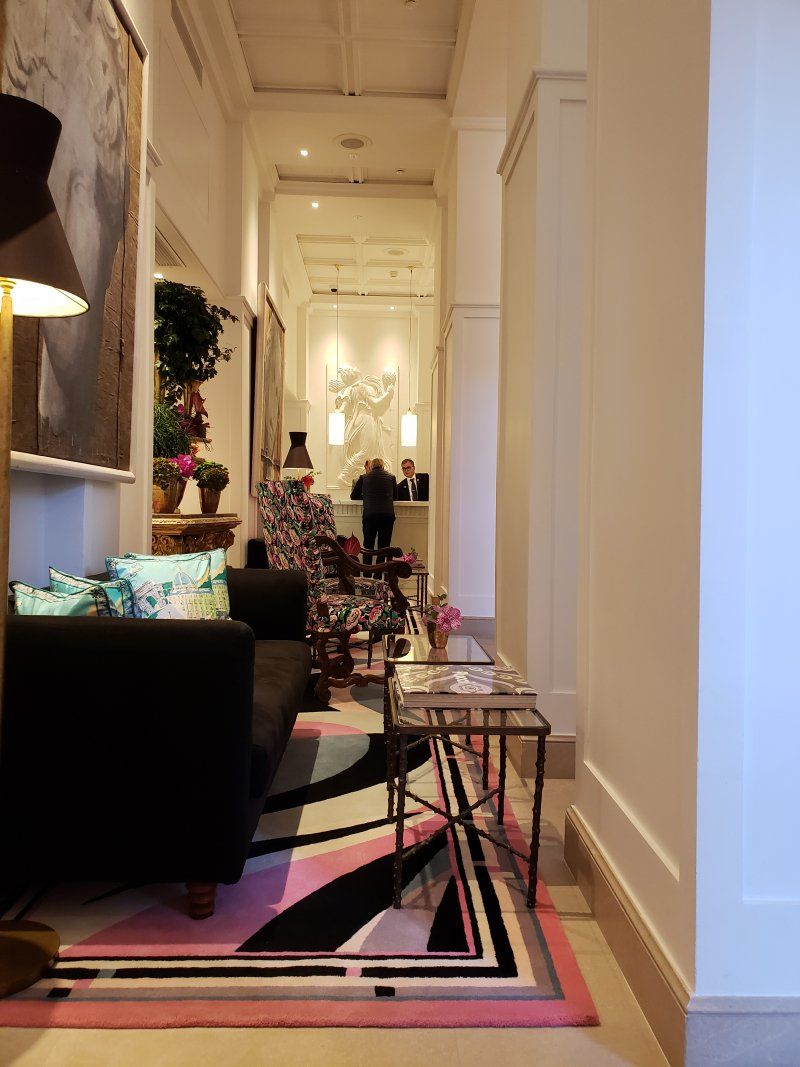 A living room with a black couch and a pink rug