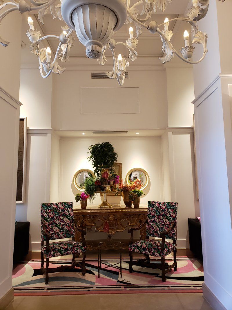A hallway with chairs and a chandelier hanging from the ceiling