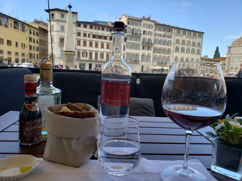 A bottle of water and a glass of wine are on a table.