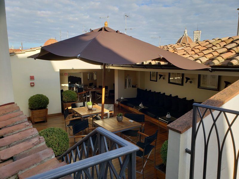 A balcony with tables and chairs under an umbrella