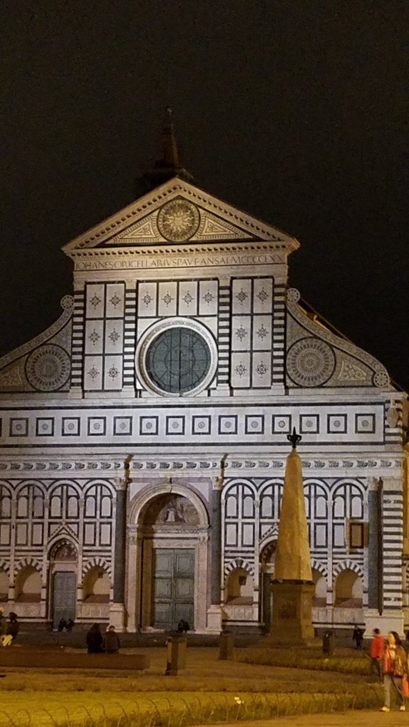 A large building with a cross on top of it is lit up at night.