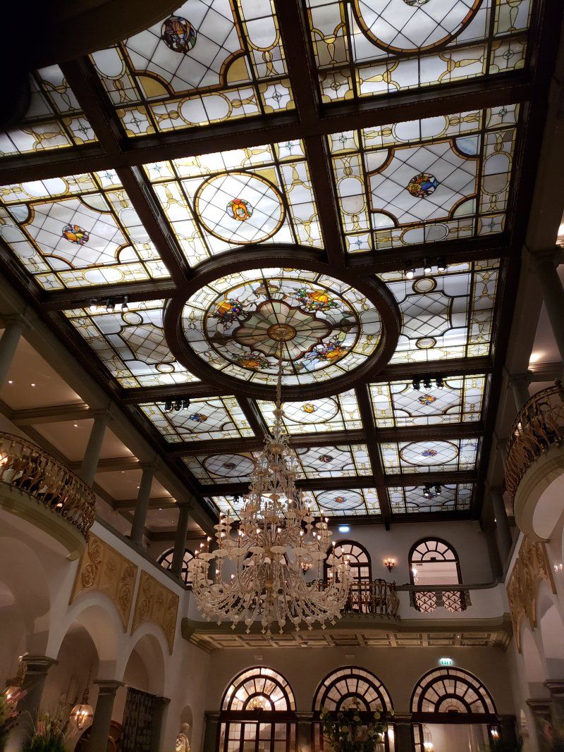A stained glass ceiling with a chandelier hanging from it