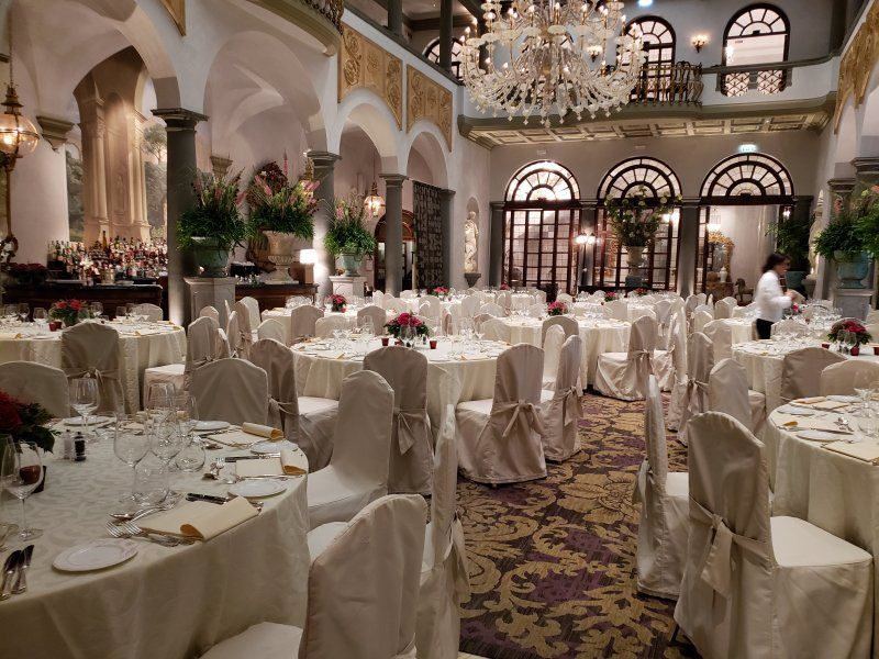 A large room with tables and chairs set up for a wedding reception