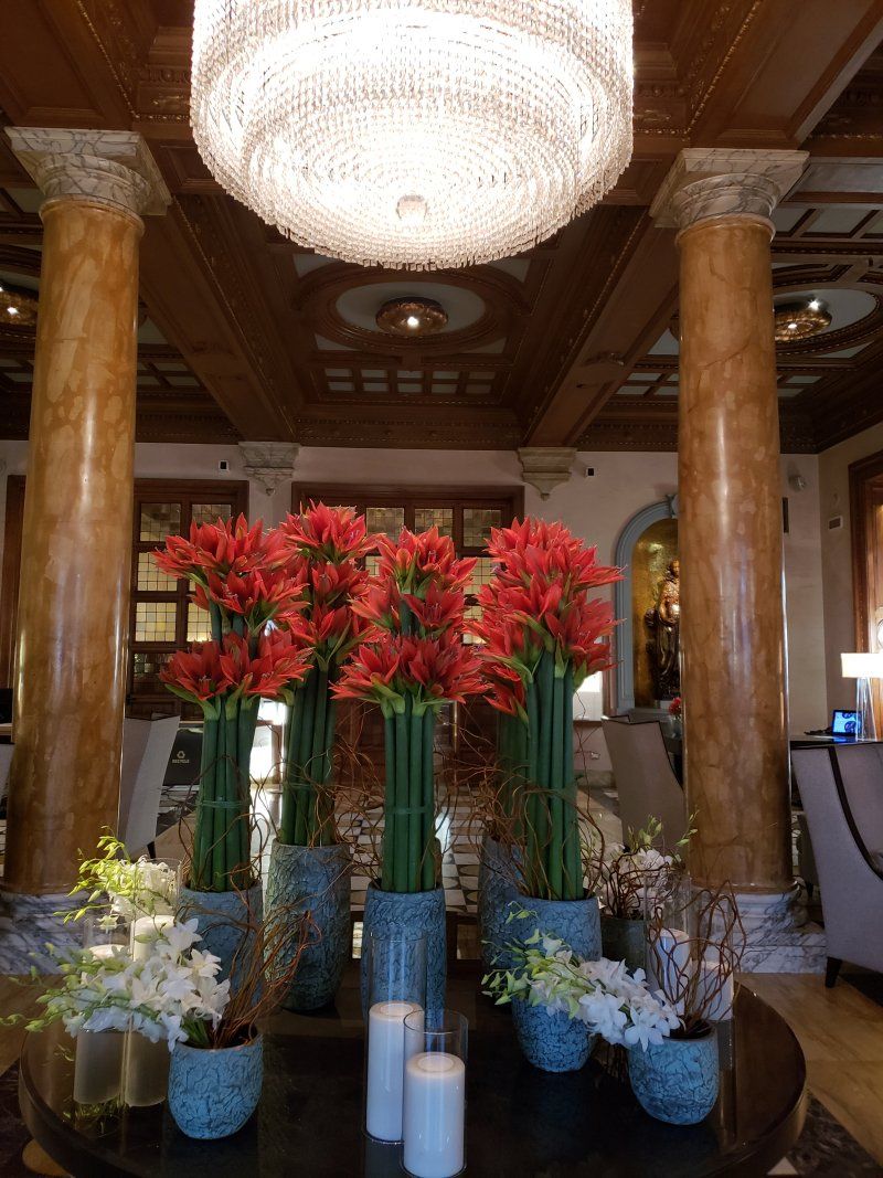 A table with vases of flowers and candles under a chandelier