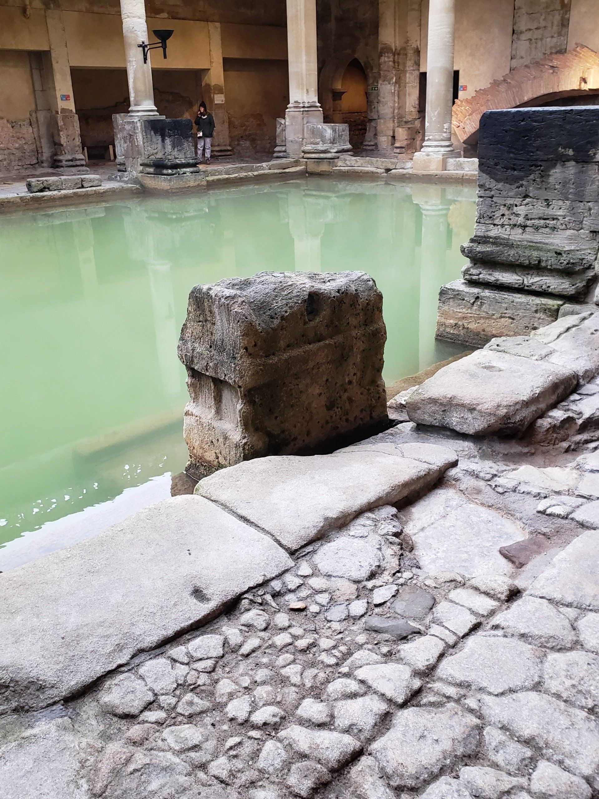 A large stone block is sitting next to a large pool of water.