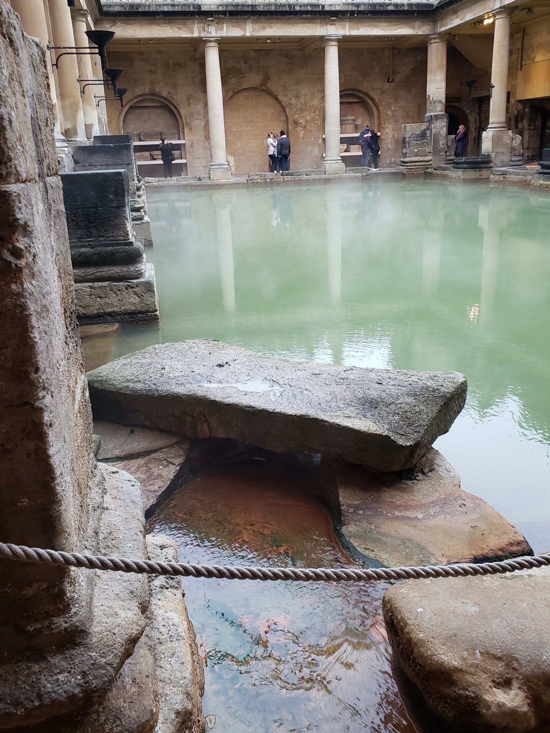 A large stone in the middle of a pool of water