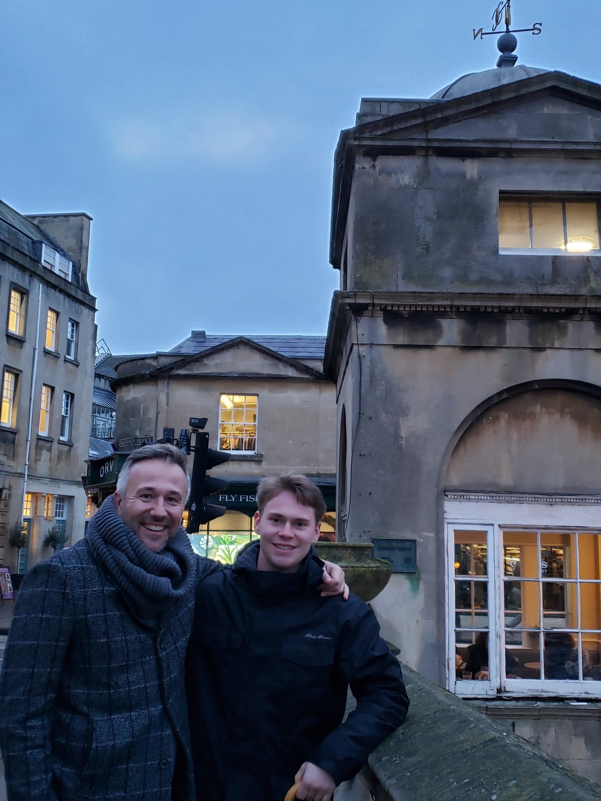 Two men are posing for a picture in front of a building