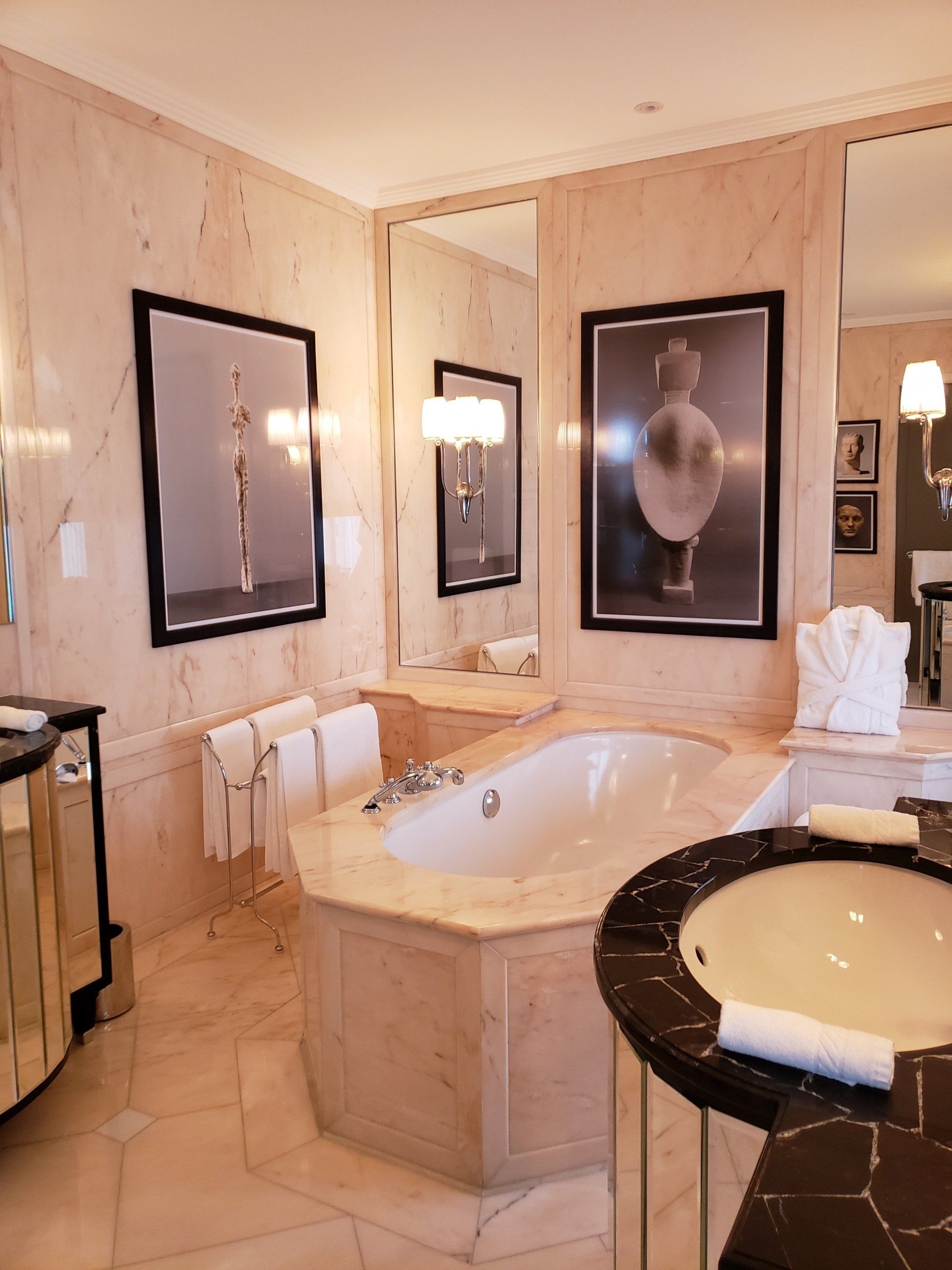 A bathroom with a tub , sink and mirrors