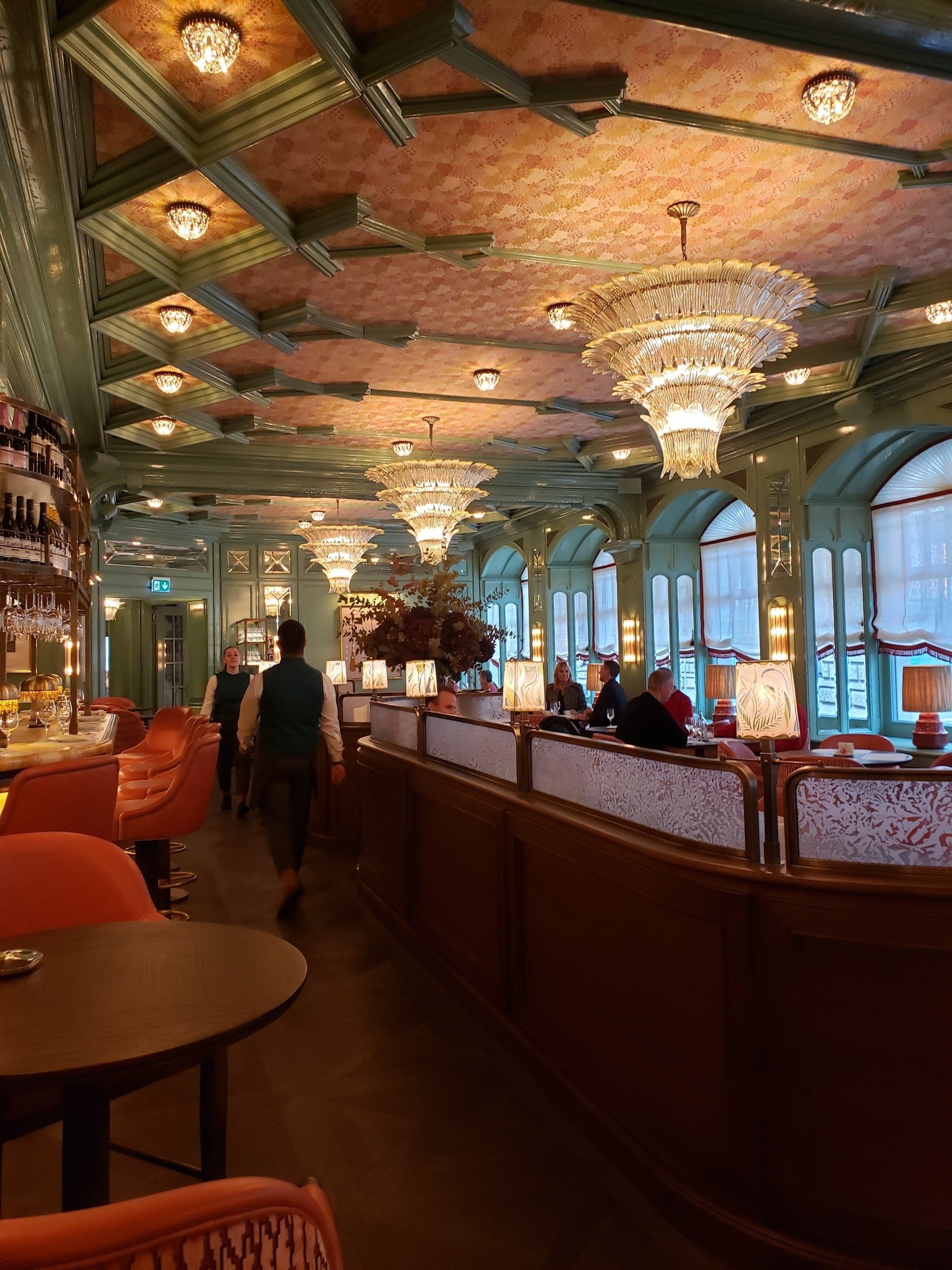 A restaurant with tables and chairs and a chandelier hanging from the ceiling.