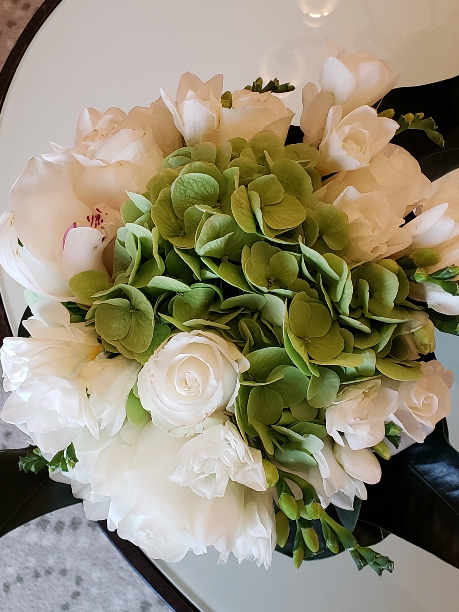 A bouquet of white and green flowers is sitting on a table.