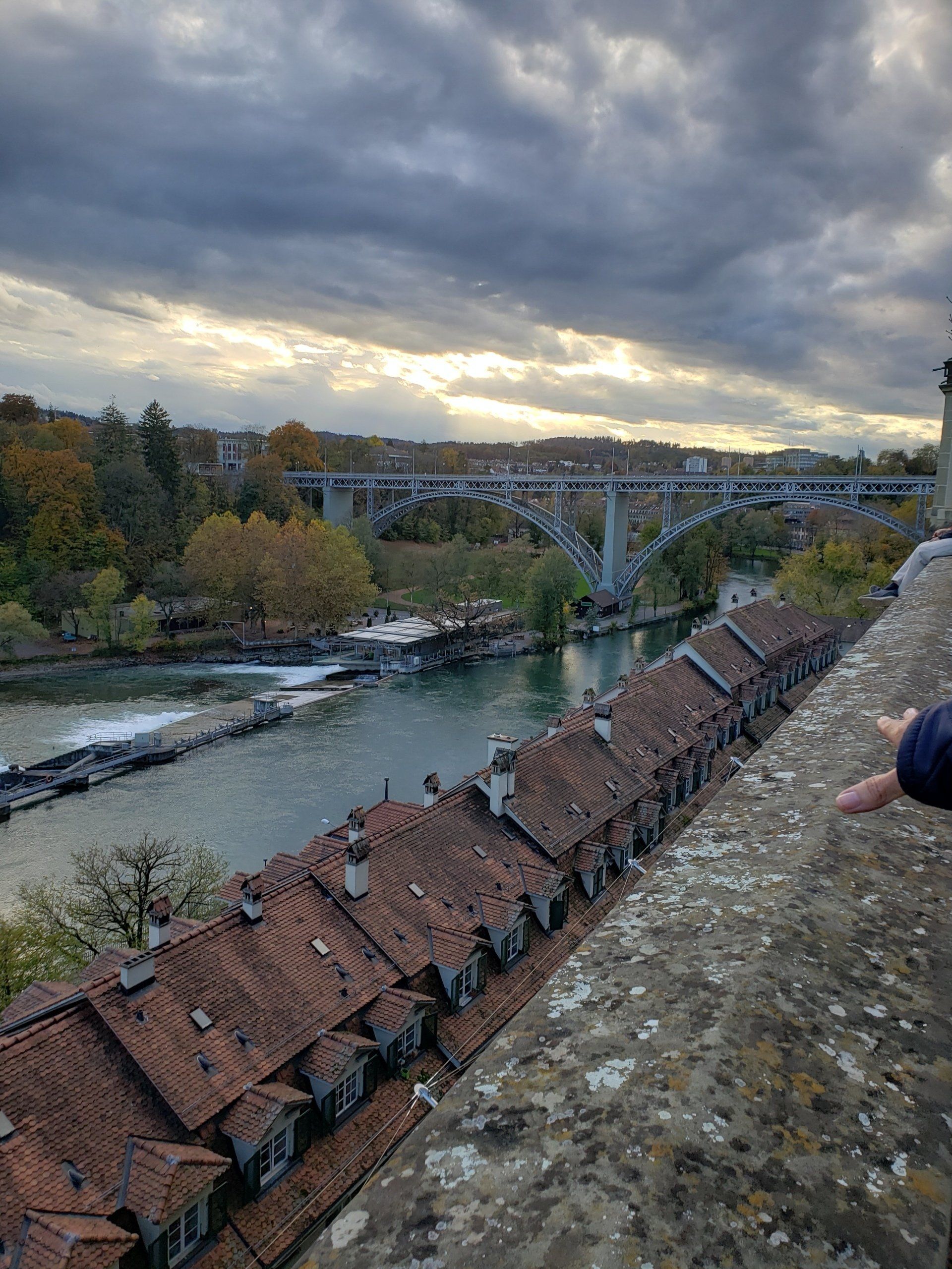 A person is standing on top of a building overlooking a river.