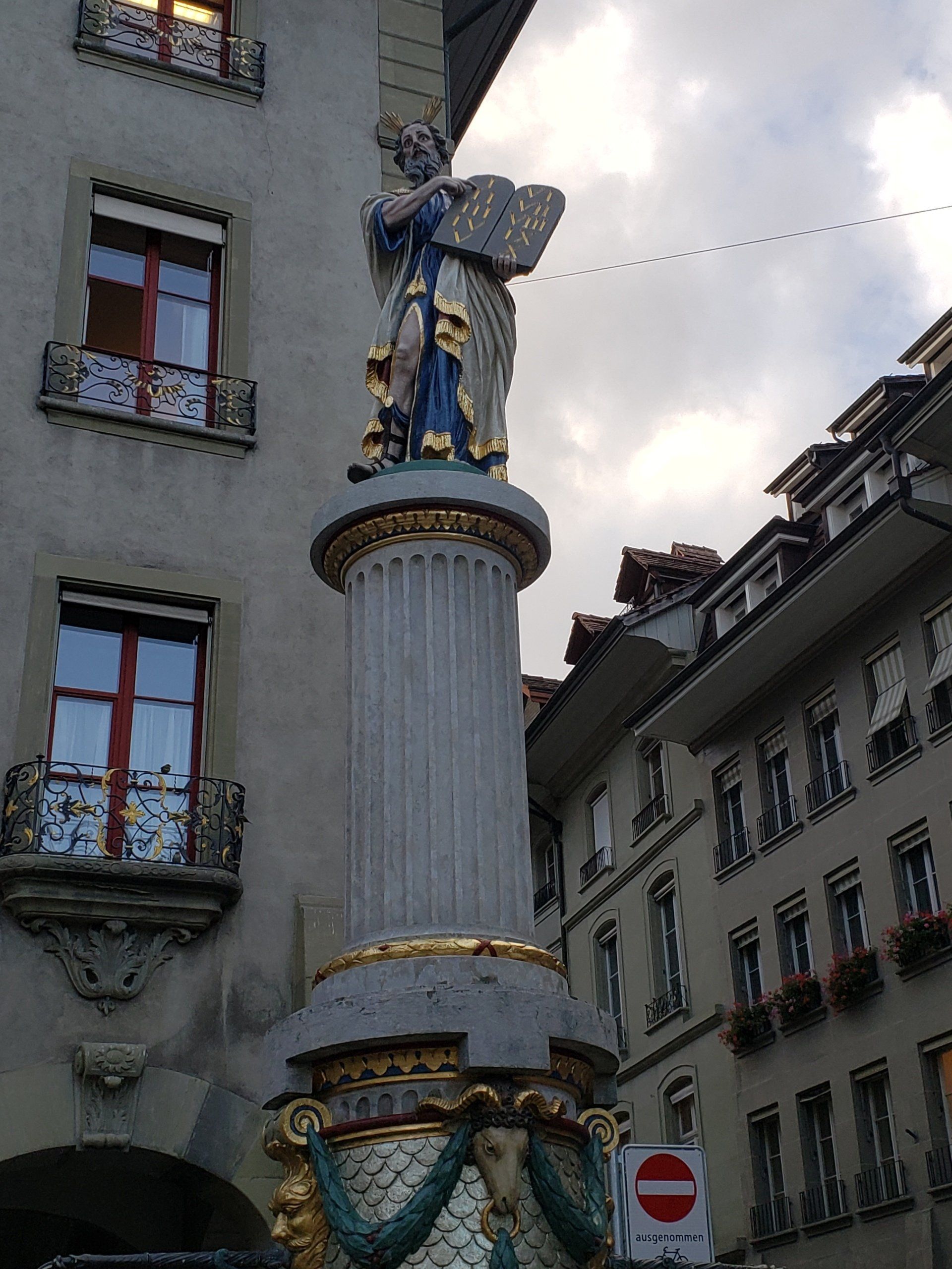 A statue of an angel on top of a pillar in front of a building