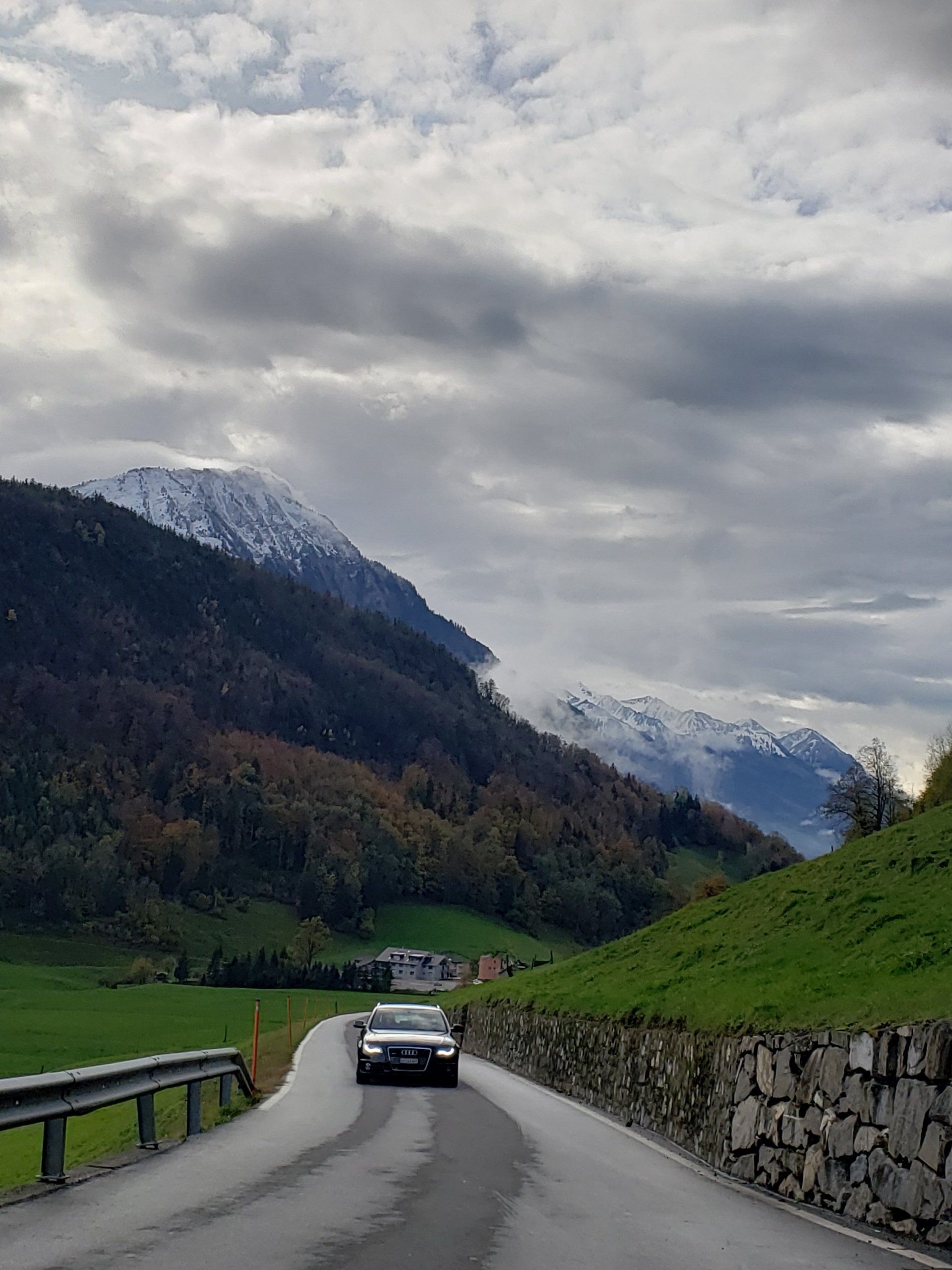 A car is driving down a road with mountains in the background