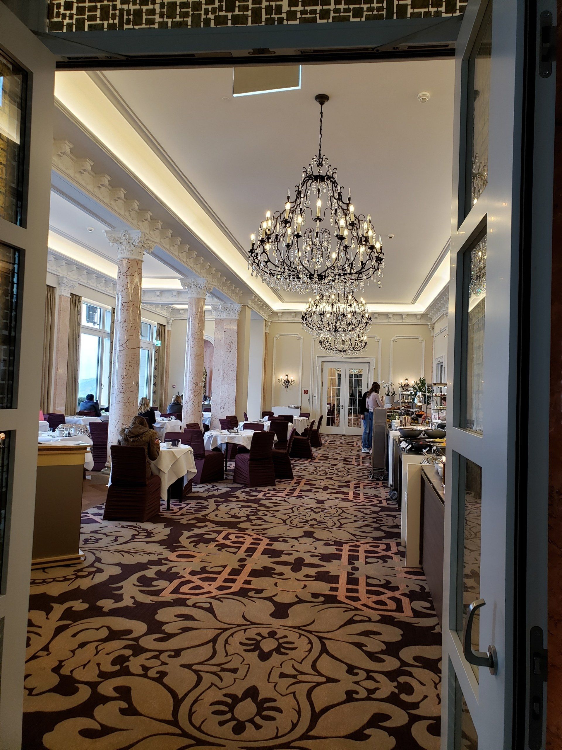 A large room with tables and chairs and a chandelier hanging from the ceiling