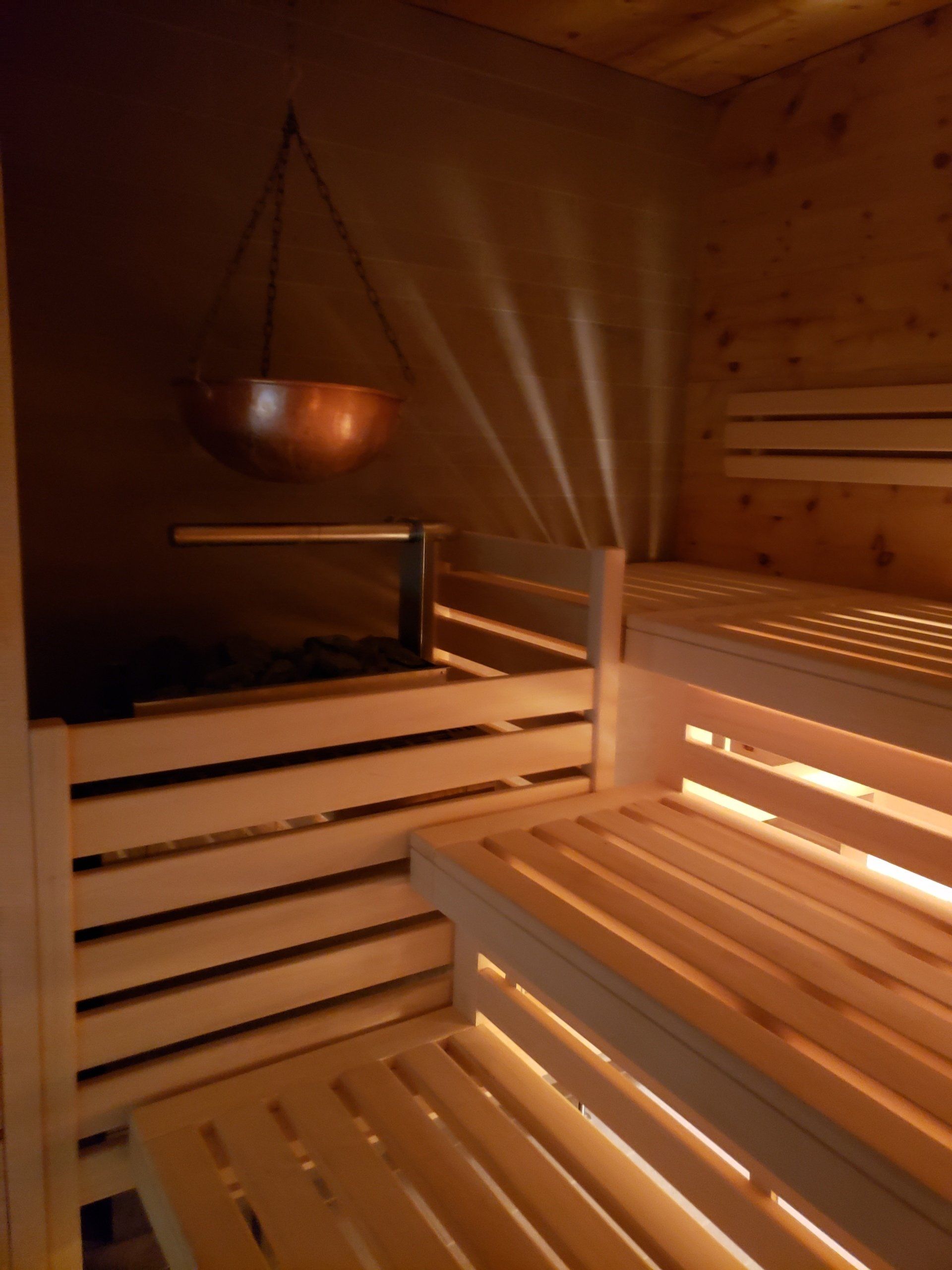 A wooden sauna with a copper pot hanging from the ceiling