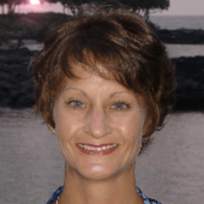 A woman is smiling in front of a body of water