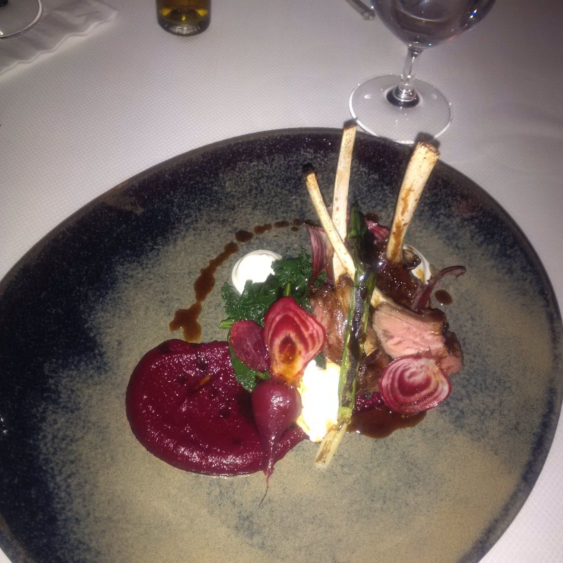 A plate of food with a glass of wine in the background