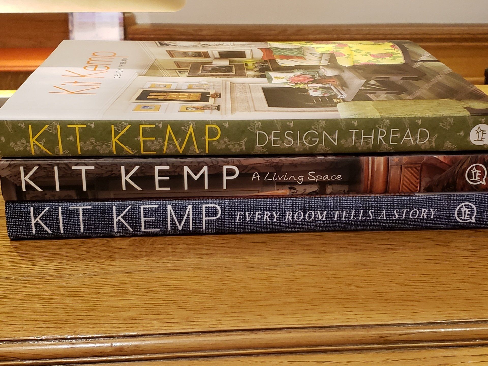 Three books by kit kemp are stacked on top of each other on a wooden table