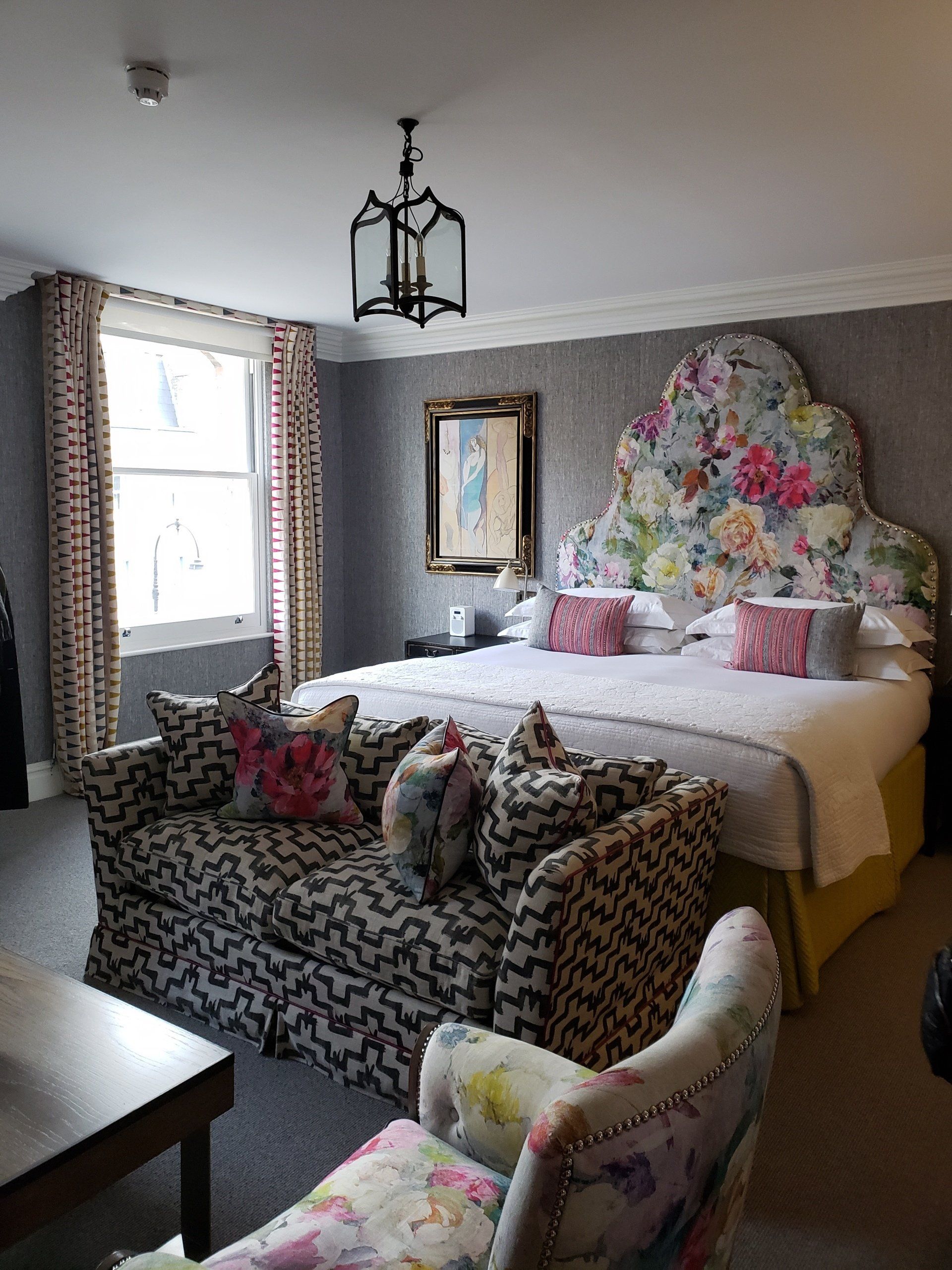 A hotel room with a large bed , couch , chair and table.