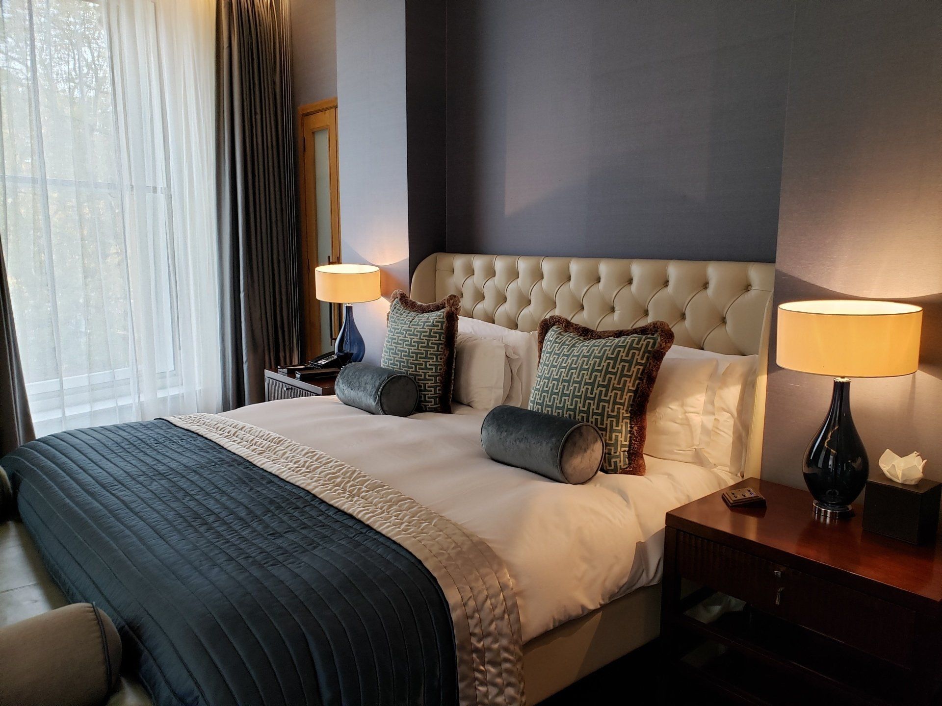 A hotel room with a large bed and two lamps