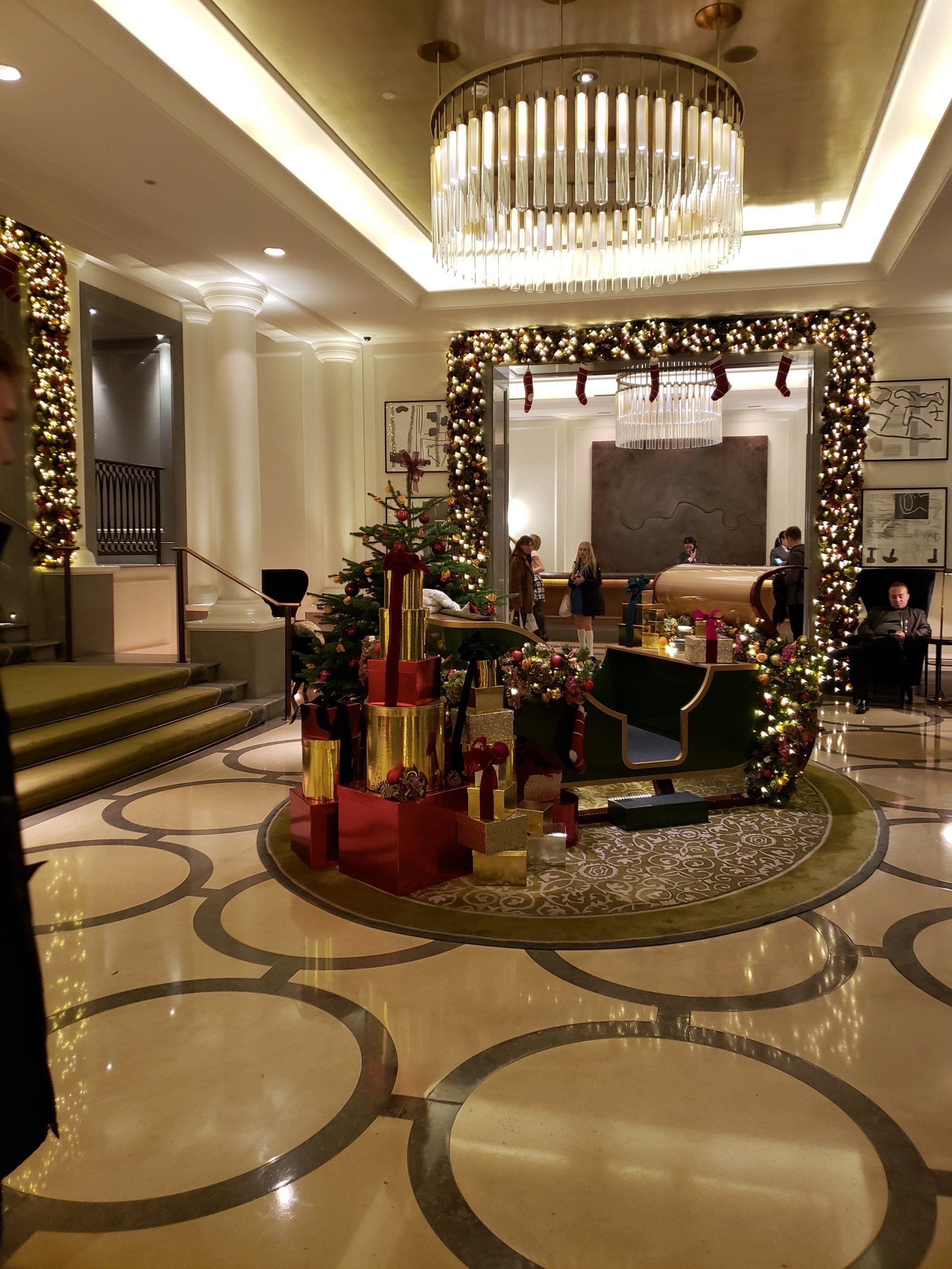 A man is standing in a lobby decorated for christmas.
