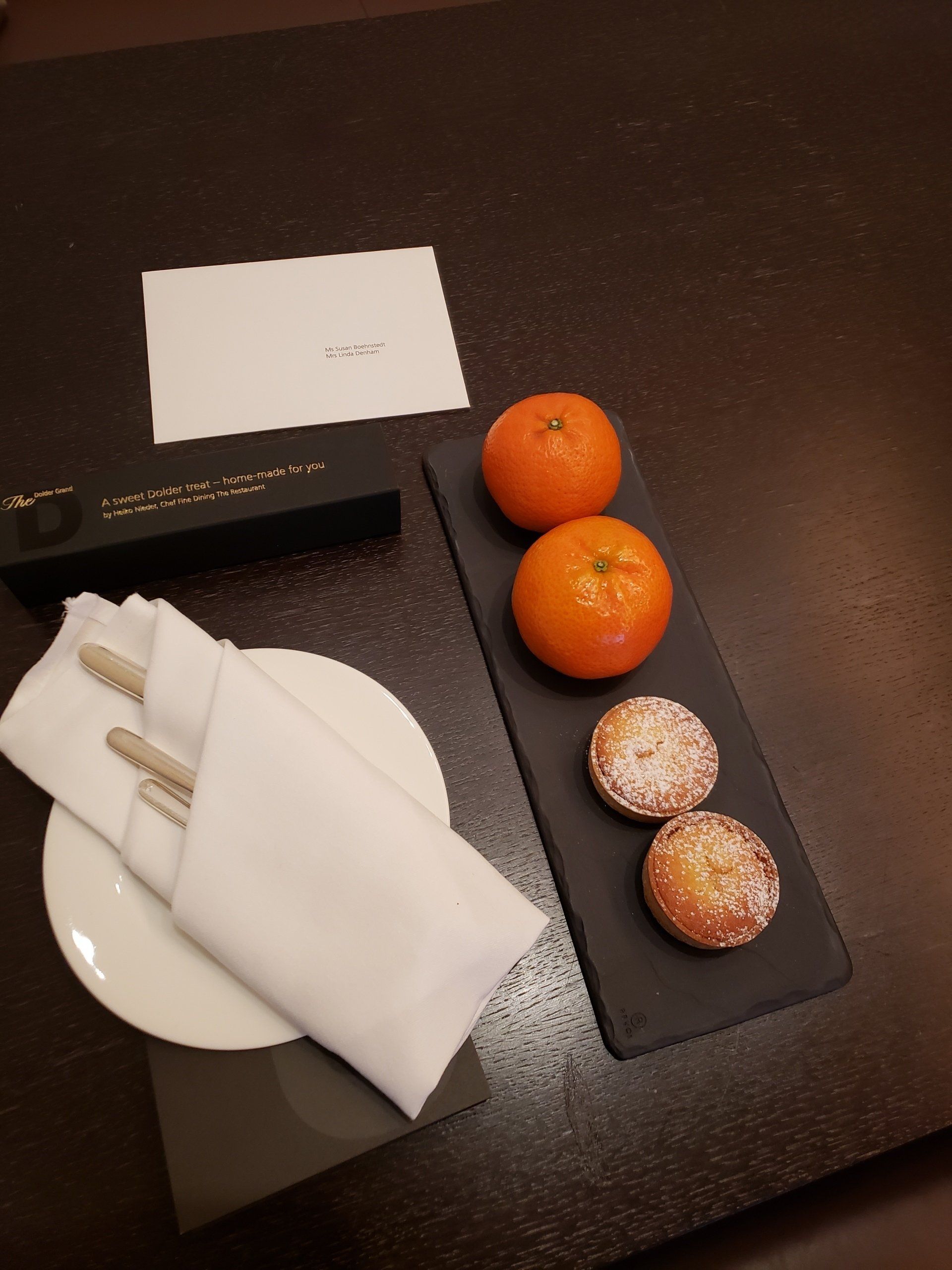 A tray of oranges and pastries on a table