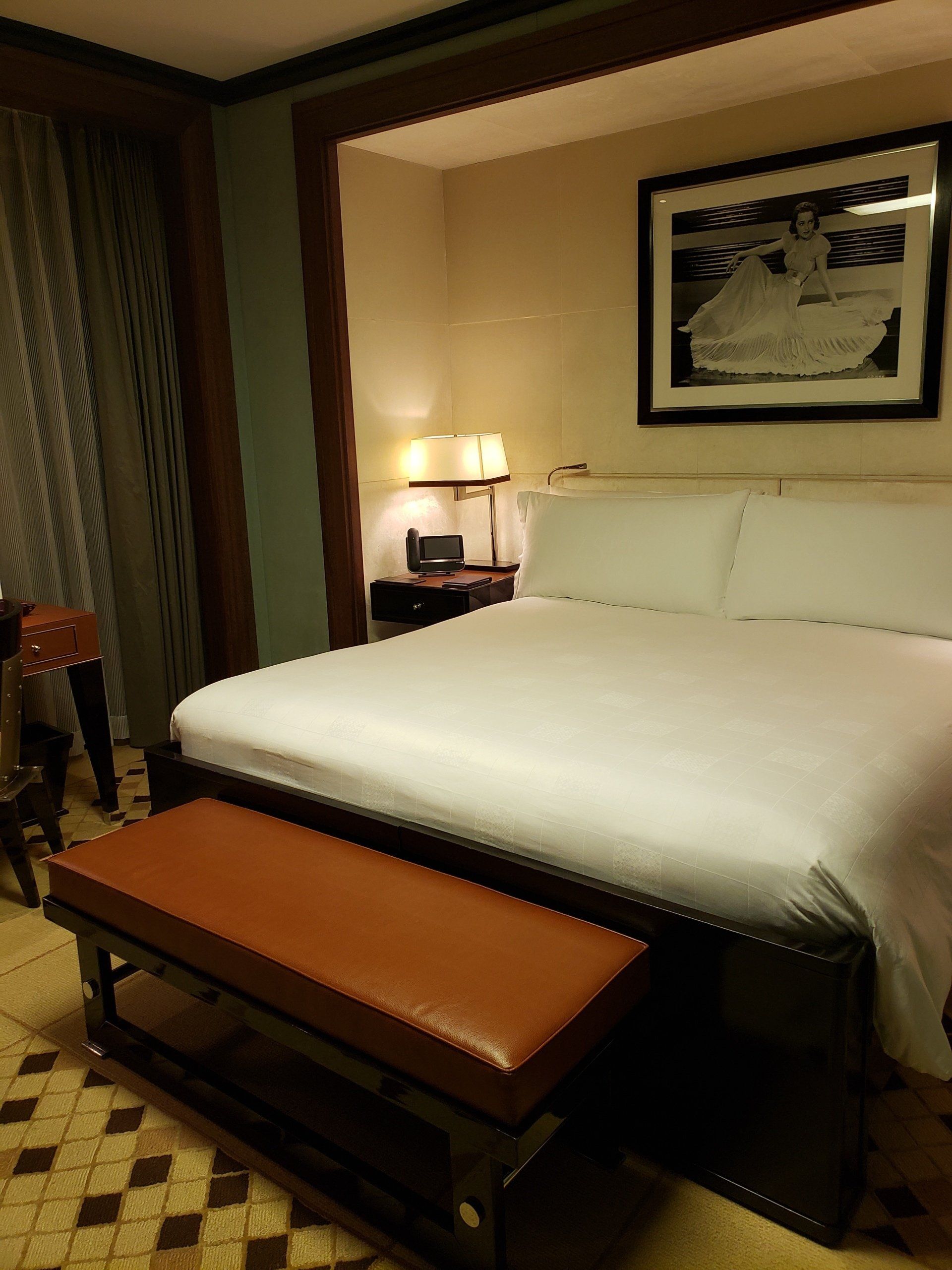 A hotel room with a large bed and a bench