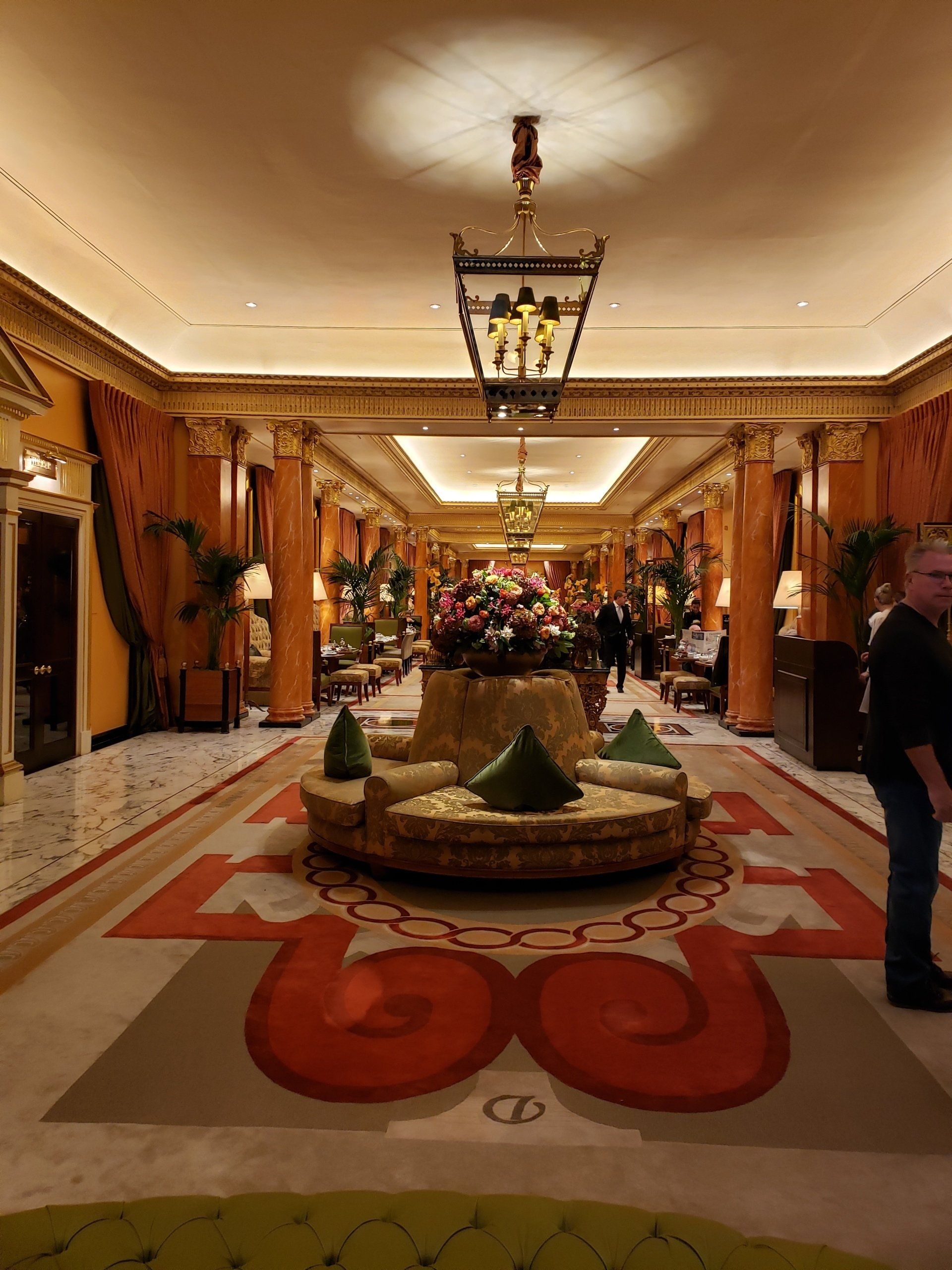 A man is standing in a long hallway with a couch in the middle