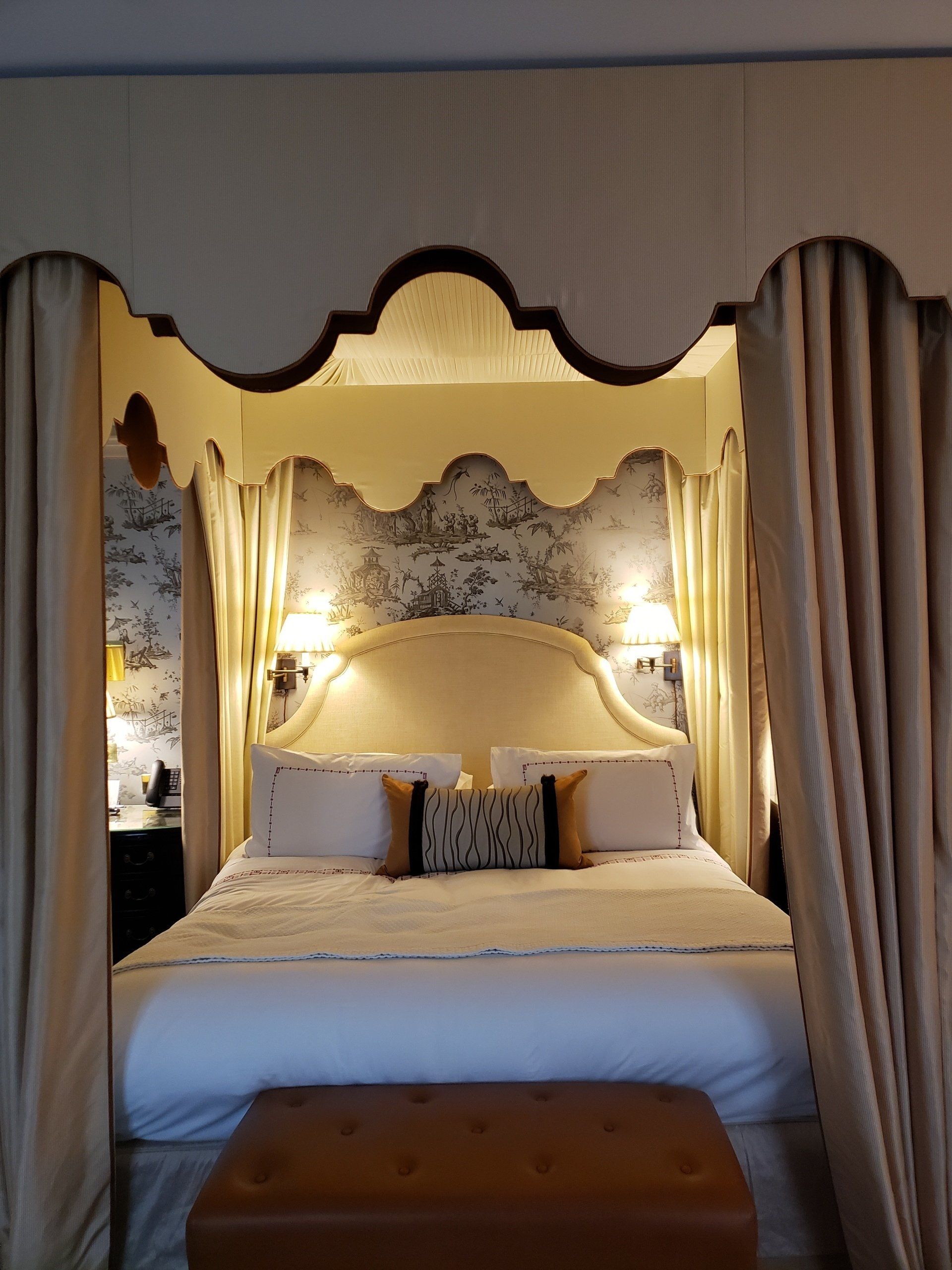 A bedroom with a canopy bed and a bench